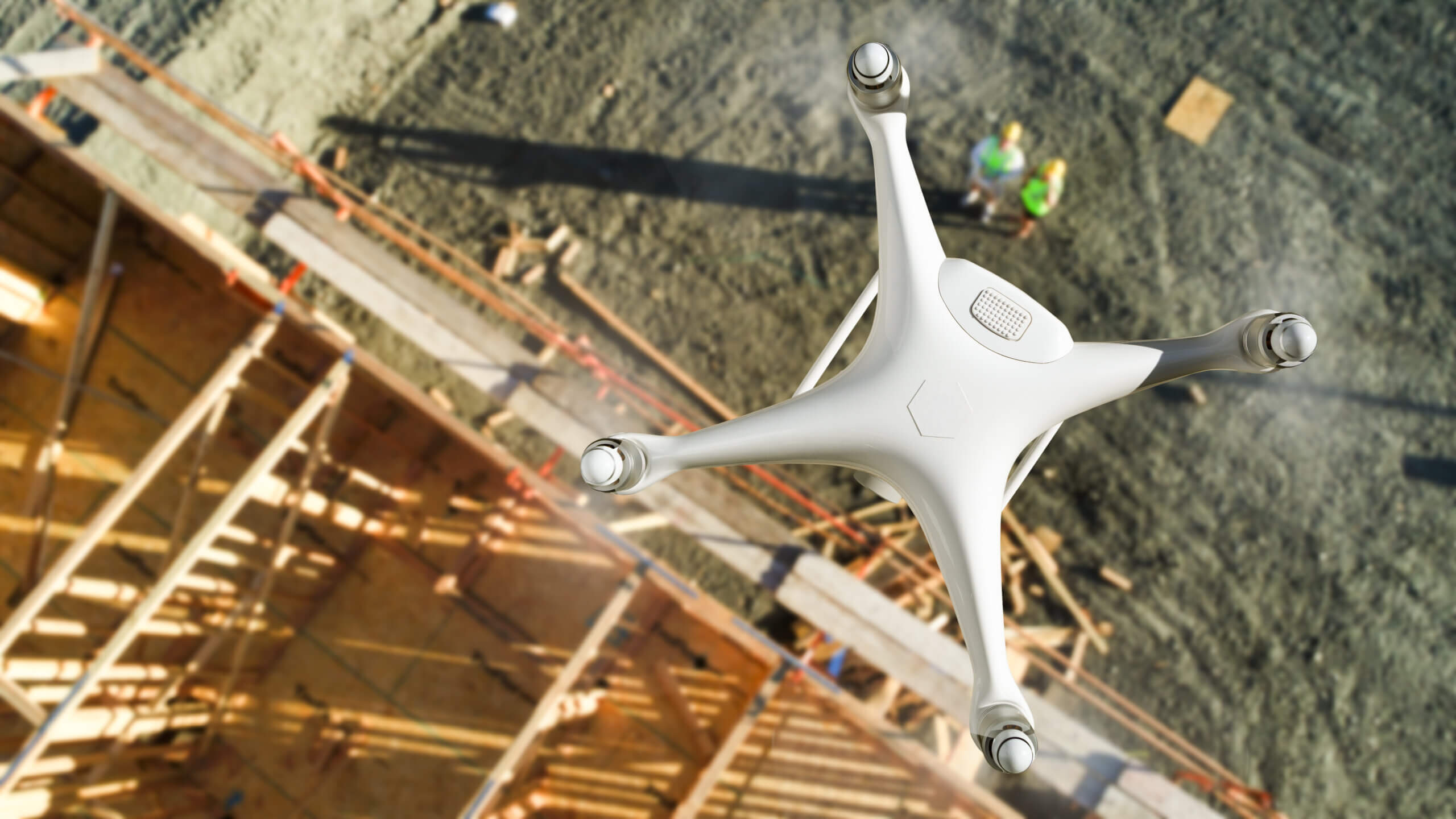 Dronă zburând deasupra unui șantier de construcții.